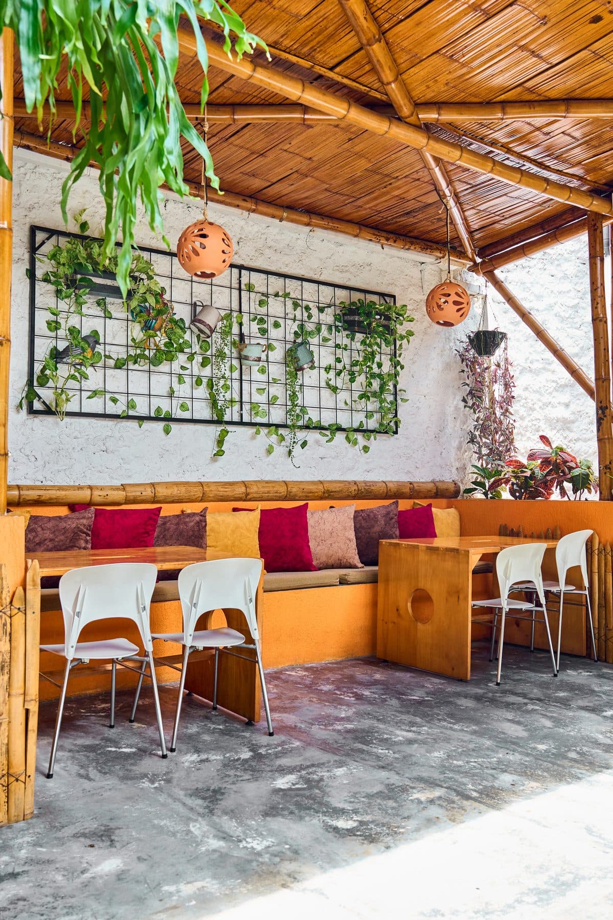 Terraza con bancas naranjas, cojines y plantas tropicales